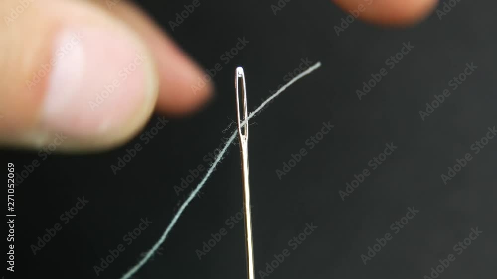Man's hand holds needle and white thread. Start of sewing Man's hand holds needle and white thread. Start of sewing