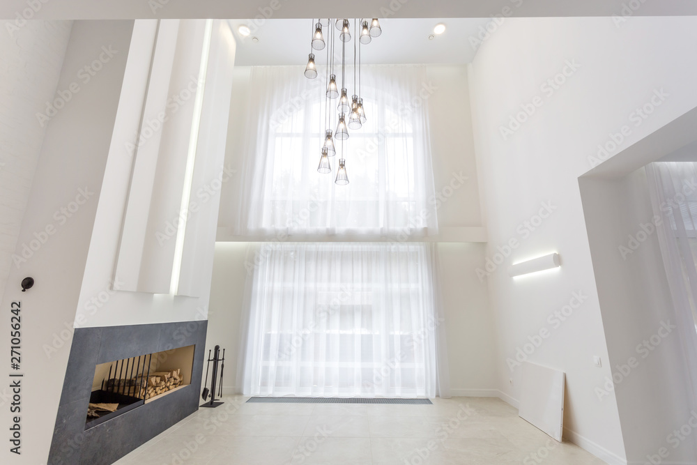 Fototapeta premium huge chandelier near fireplace for bright interior loft in front of a large panoramic window