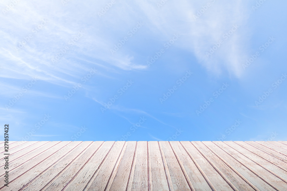 Perspective view on a wooden table top on a bright blue sky background