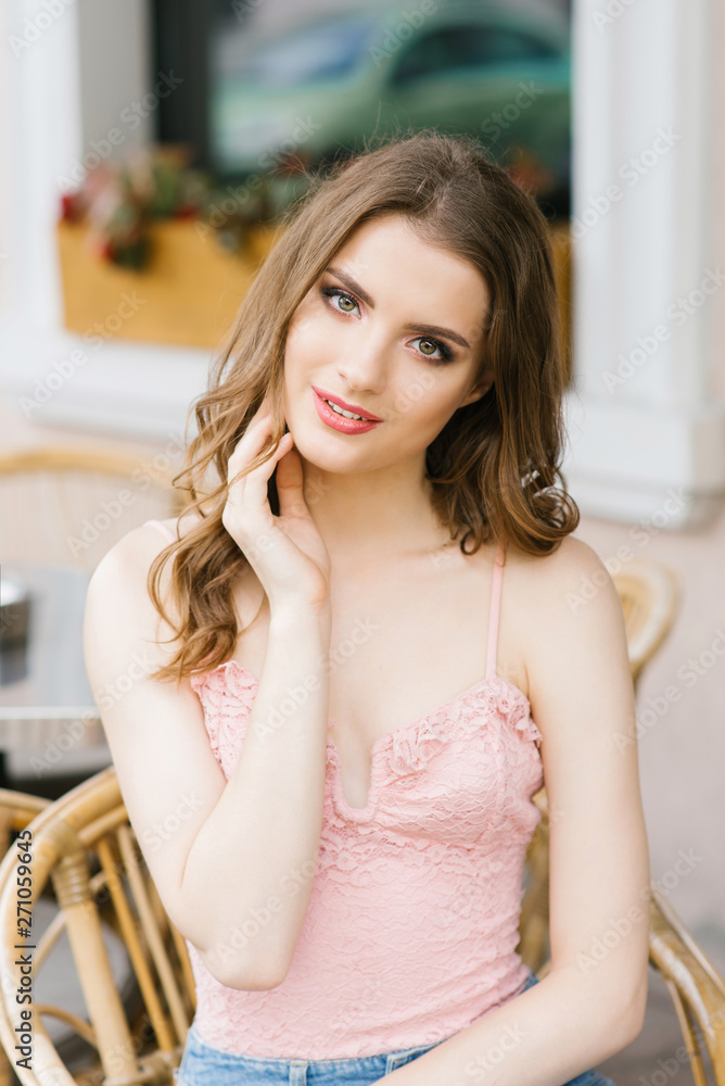 Portrait of a beautiful girl in a pink top sitting at a street cafe table Portrait of a beautiful girl in a pink top sitting at a street cafe table