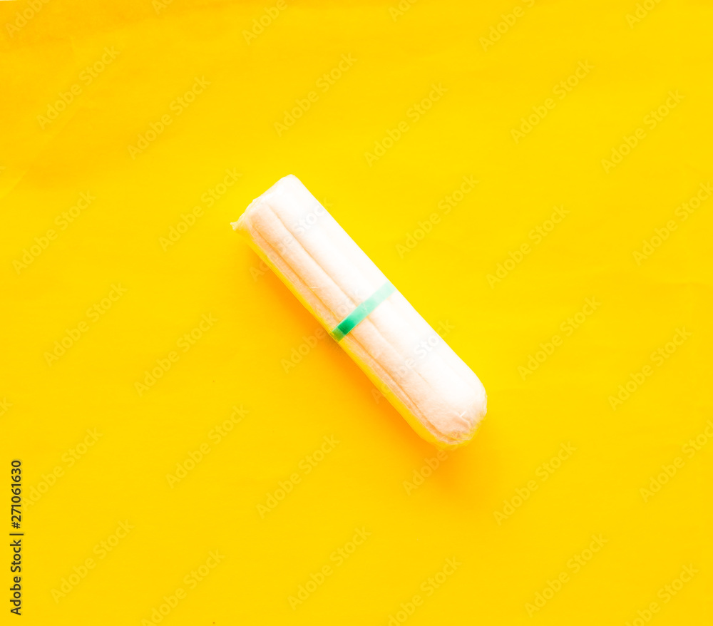The concept of critical days, menstruation. Isolated tampons on a yellow plan, closeup. The concept of critical days, menstruation. Isolated tampons on a yellow plan, closeup.