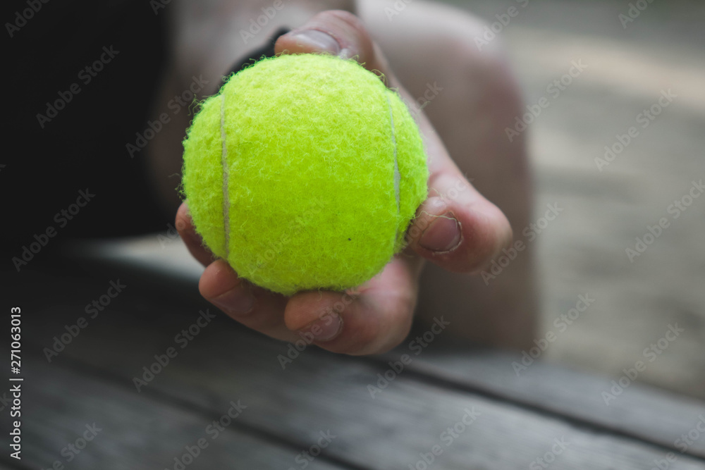 man holding a green tennis ball in the street