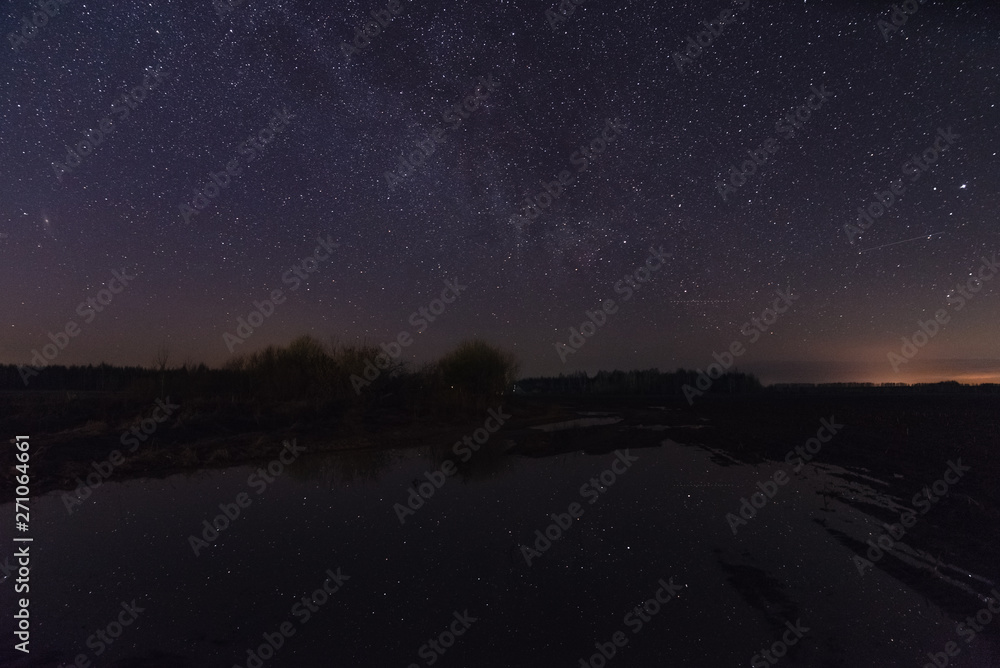 Reflection of stars in a big puddle at night in spring