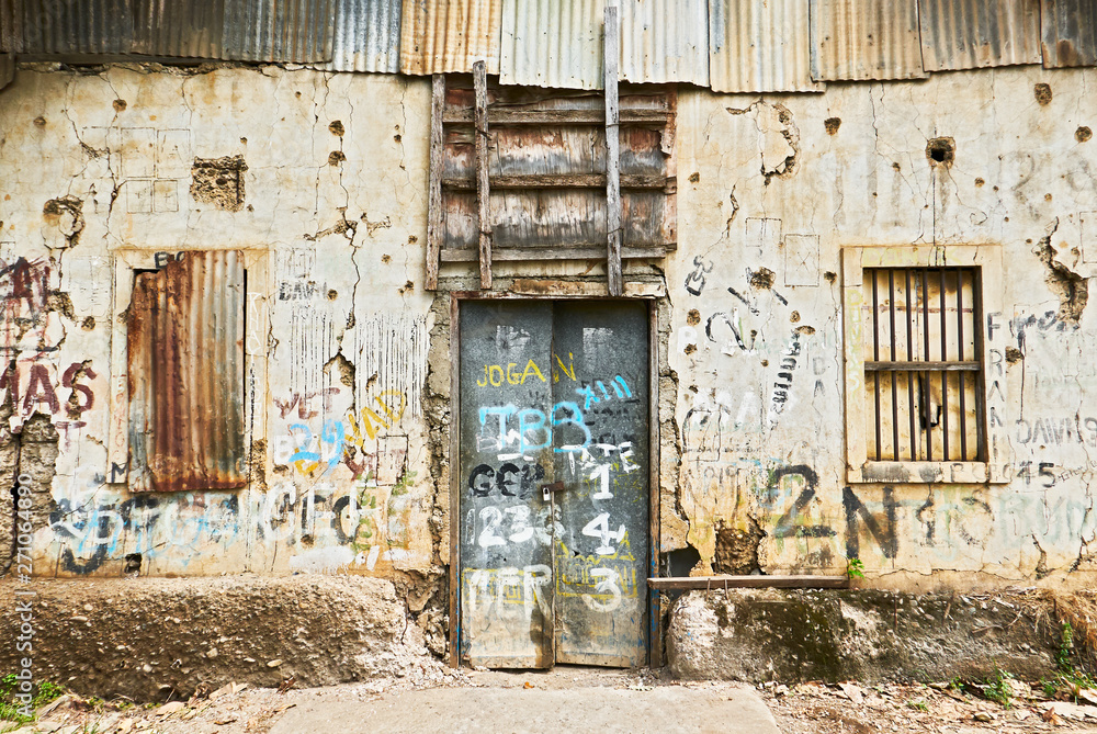 Puerto Princesa City, Palawan, Philippines: Close-up view of the front of an abandoned ruined building with closed windows and door Puerto Princesa City, Palawan, Philippines: Close-up view of the front of an abandoned ruined building with closed windows and door