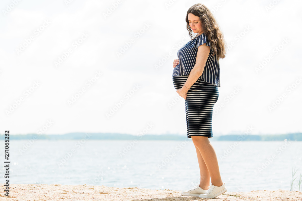 Cheerful pregnant woman with long hair standing on the beach. Happy pregnancy concept. Cheerful pregnant woman with long hair standing on the beach. Happy pregnancy concept.