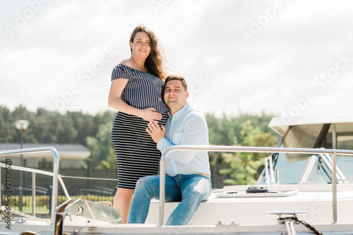 Cheerful pregnant woman with husband on yacht. Happy pregnancy concept. Young family on vacation. Candid photo. © beatleoff