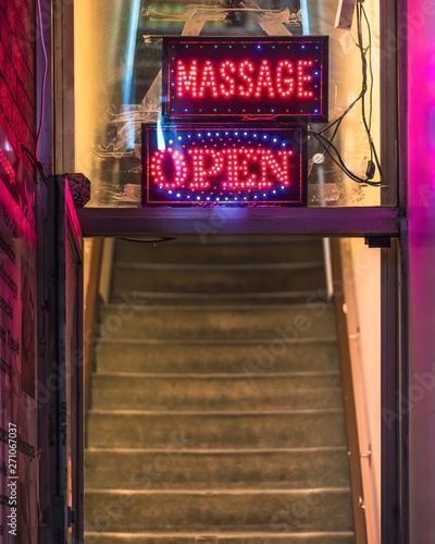 Obraz na płótnie A 'Massage Open' sign hanging in the window of a massage parlour with blue and red LED lights