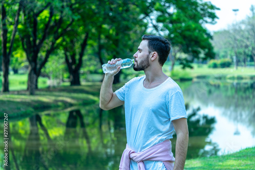 Caucasion man thirsty and drinking water from pet bottle in public park