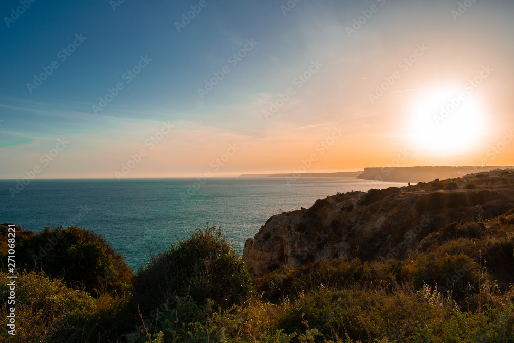 Beautiful sunset and colorful sky above atlantic ocean and cliffs on praia De Camilo Popular and famous place in Algarve, Portugal 