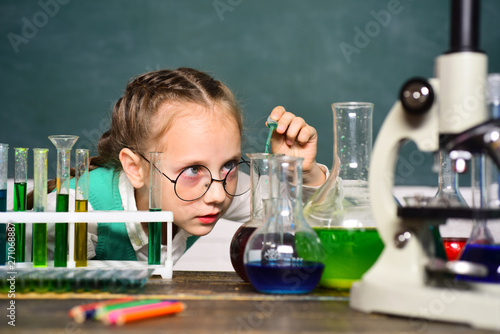 Back to school and home schooling. Science and education concept. Happy little scientist making experiment with test tube. Portrair close up. photo