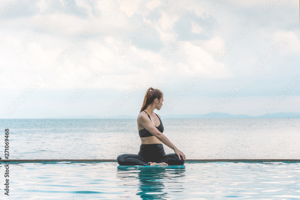 Happy Asian woman wearing black sport wear practice yoga Seated Twist pose on the pool above the beach with beautiful sea in Tropical island,Feeling comfortable and relax in holiday,Vacations Concept Happy Asian woman wearing black sport wear practice yoga Seated Twist pose on the pool above the beach with beautiful sea in Tropical island,Feeling comfortable and relax in holiday,Vacations Concept