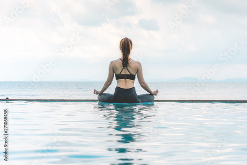Vacation of Beautiful Attractive Asian woman relaxing in yoga lotus pose on the pool above the beach with beautiful sea in Tropical island Feeling comfortable and relax in holiday Vacations Concept
