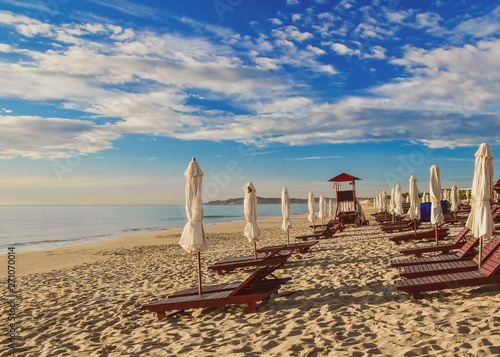 Obraz na płótnie Sun loungers and umbrellas on an empty sandy beach. Summer sunny cloudy blue sky. Cam Ranh. Vietnam. w salonie