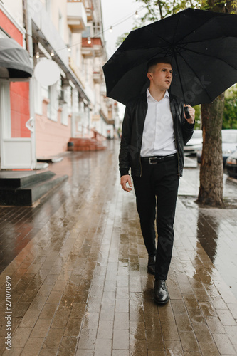 Young man walking with umbrella in the rain