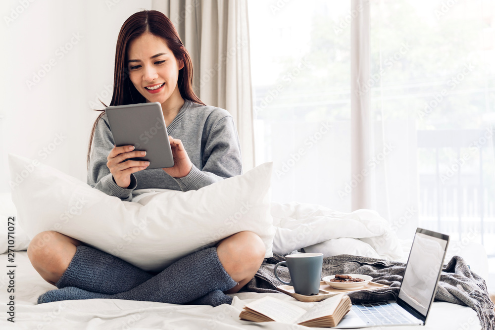 Woman relaxing and using digital tablet computer on the bed at home.woman checking social apps and working..Communication and technology concept Woman relaxing and using digital tablet computer on the bed at home.woman checking social apps and working..Communication and technology concept