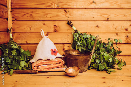 Various sauna accessories in Finnish sauna steam room. Felt hat prevents hair damage, keeps head from over heating, broom made from branches are for skin massage stimulation and increases blood flow. photo