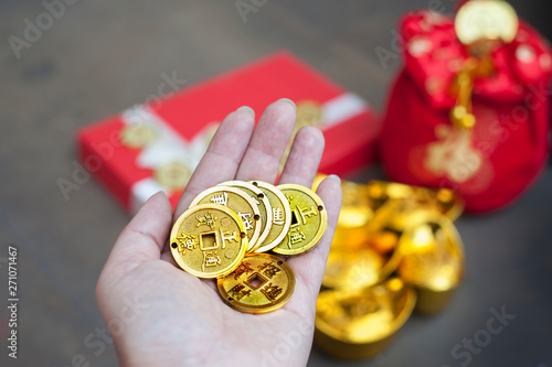 Chinese gold coins on hand, New Year Gift, red pouch money bag, gold ingots with Chinese character meaning whealth, rich, gold, luck, healthy. photo