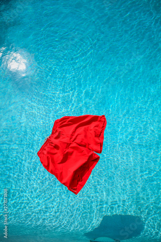 red swimming trunks floating in a swimming pool - Caught With Your Pants Down