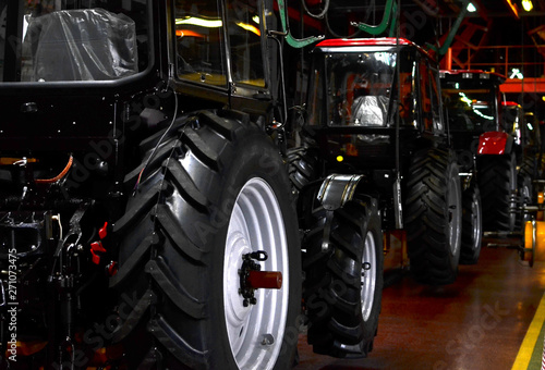 Tractor Manufacture work. Assembly line inside the agricultural machinery factory. Installation of parts on the tractor body - Image