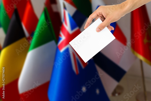 Election or referendum in Great Britain. Voter holds envelope in hand above vote ballot. British and European Union flags in background