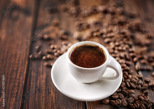 Hot coffee cup and beans on wood table background