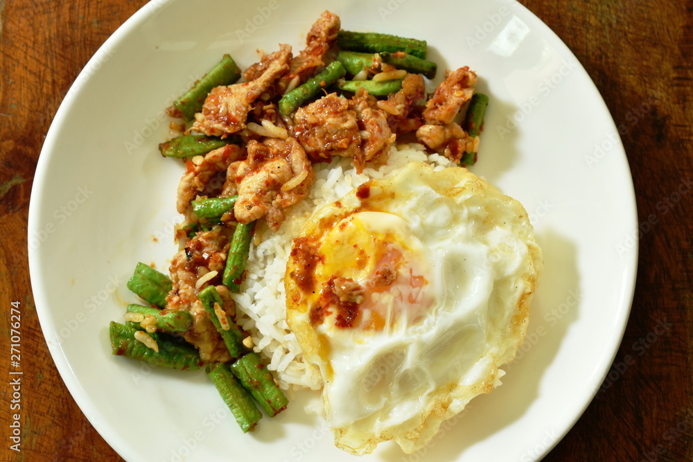 spicy stir fried pork with yard long bean curry topping egg on rice spicy stir fried pork with yard long bean curry topping egg on rice