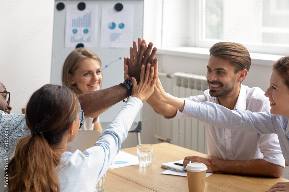 Happy motivated diverse members of business team join hands together Happy motivated diverse members of business team join hands together