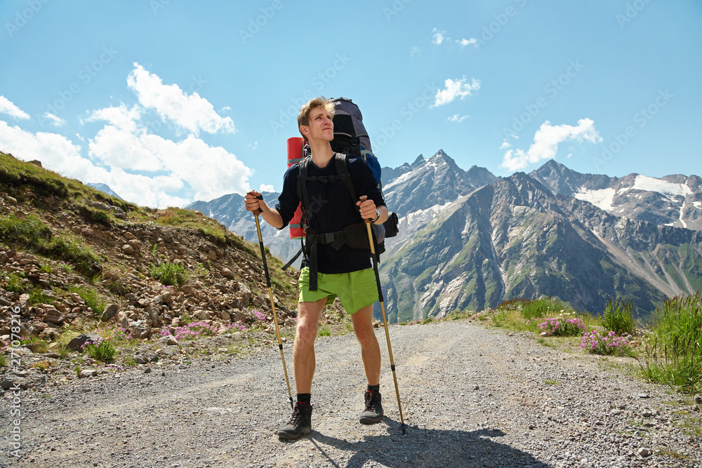 climber on trail in the mountains. a man with backpack in a hike
