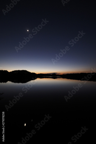 The Moon and Venus over an exceptionally calm Paurotis Pond in Everglades National Park, Florida in late twilight.