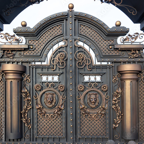 Fototapeta New forged metal massive gates with a wicket and two arches, golden gray, made in antiquity