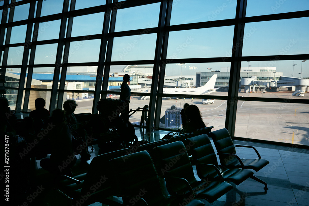 silhouette of a group of people in an airport waiting hall silhouette of a group of people in an airport waiting hall