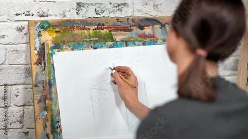 Painter woman drawing sketch on canvas using gray pencil close-up back view photo