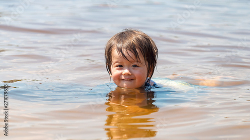 Toddler boy swimming in a big lake on a summer day © Tierney