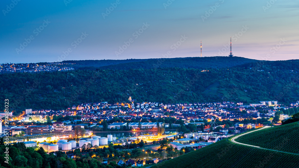 Germany, Illuminated houses of stuttgart city behind vineyards with television tower building on top of green mountains after sunset