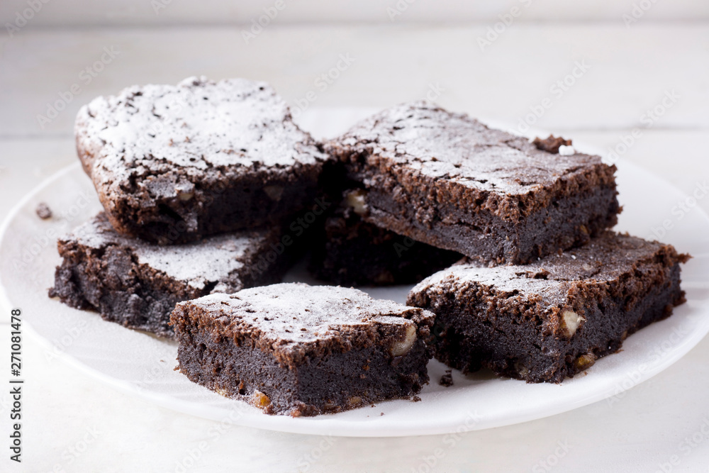 Delicious chocolate cake on a white plate, dusted with icing sugar. Homemade baking. Traditional American Pie. Delicious chocolate cake on a white plate, dusted with icing sugar. Homemade baking. Traditional American Pie.