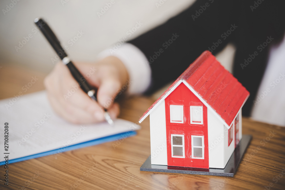 Buying and renting new home concept. Close up of signing rental agreement or sale purchase contract sitting on couch indoors, starting family life, approved loan to buy real estate Buying and renting new home concept. Close up of signing rental agreement or sale purchase contract sitting on couch indoors, starting family life, approved loan to buy real estate