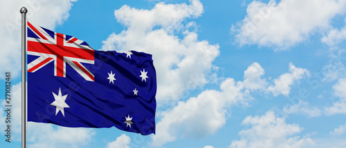 Australia flag waving in the wind against white cloudy blue sky. Diplomacy concept, international relations.