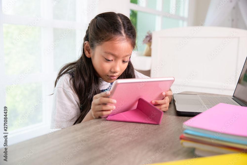 Little asian girl enjoy playing tablet pc at home in daytime Little asian girl enjoy playing tablet pc at home in daytime