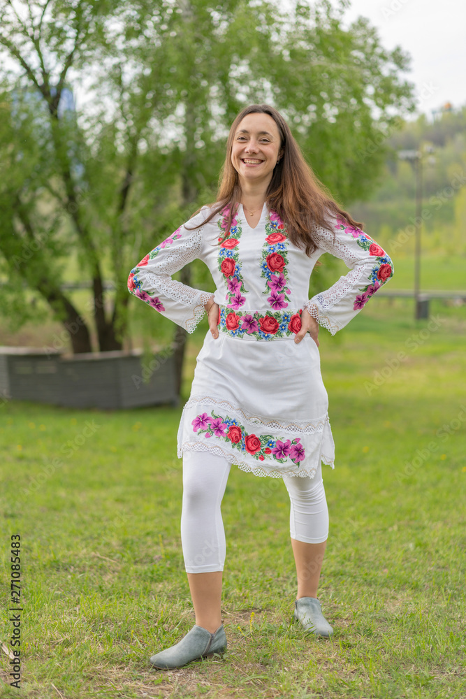 Happy young woman in the Ukrainian national clothes in the park. Woman in embroidery. Vertical photo Happy young woman in the Ukrainian national clothes in the park. Woman in embroidery. Vertical photo