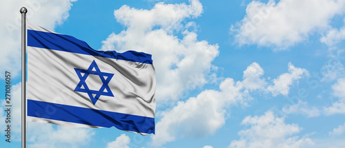 Israel flag waving in the wind against white cloudy blue sky. Diplomacy concept, international relations.