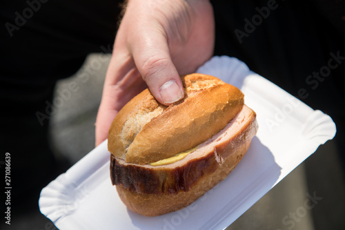 Wallpaper Mural Mann isst Bayrischen Leberkäse auf Brötchen als schnellen Snack unterwegs auf Einwegteller Torontodigital.ca
