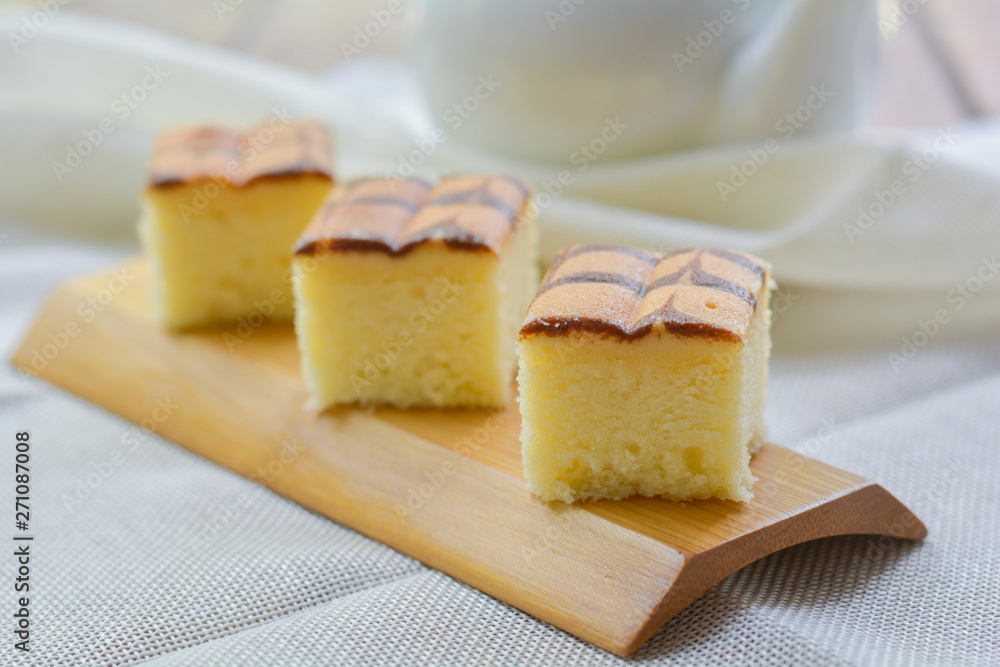 Cube cut of butter cake on wooden tray and table for served in party. Delicious dessert eat with tea and coffee in morning.
