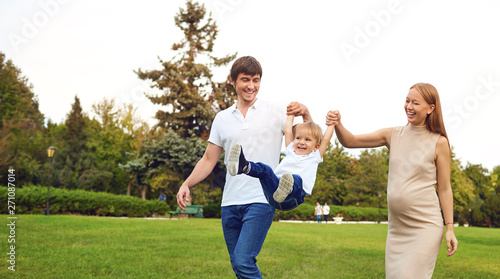 Happy family playing with baby in the park.