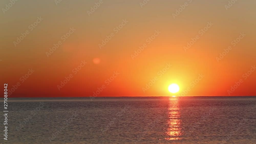 sunrise over the calm sea. the sun rises right above the sea and a big beautiful ray is reflected on the surface of the water. the sky is filled with golden orange sunrise over the calm sea. the sun rises right above the sea and a big beautiful ray is reflected on the surface of the water. the sky is filled with golden orange