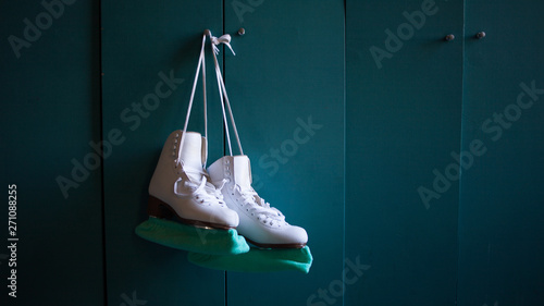 Women's figure skates hang on the locker door