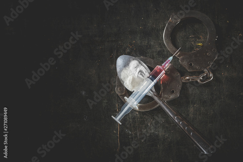 Drug syringe and cooked heroin on spoon and handcuffs . Concept - punishment for possession of narcotic drugs, Copy space