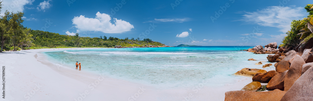 Panoramic shot of wide picturesque white sand beach, Seychelles, La Digue, Anse Cocos. Couple enyoing vocation time concept