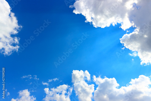 The Holy Light comes from heaven. Sunlight pass through white cumulus clouds with bright blue sky. Clouds is lit from behind by the sun's rays. Natural background with copy space. photo