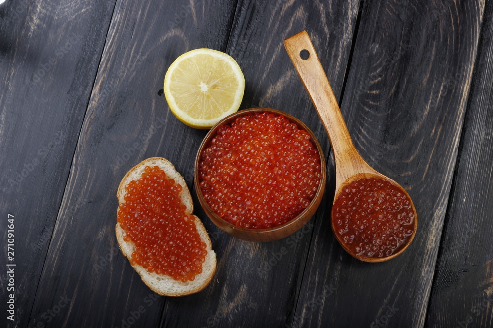 red caviar on wooden cup and wooden spoon on wooden background. top view red caviar on wooden cup and wooden spoon on wooden background. top view