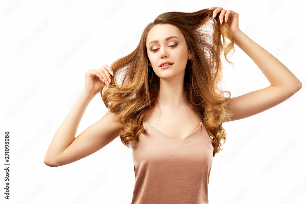 slender young woman is holding with both hands the locks of long curly hair and sweet smiles. Studio portrait on isolated white background slender young woman is holding with both hands the locks of long curly hair and sweet smiles. Studio portrait on isolated white background